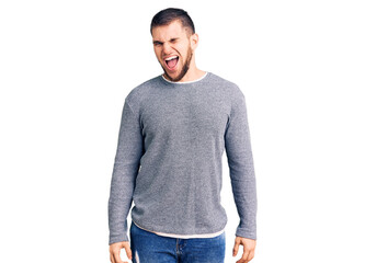 Young handsome man wearing casual sweater winking looking at the camera with sexy expression, cheerful and happy face.