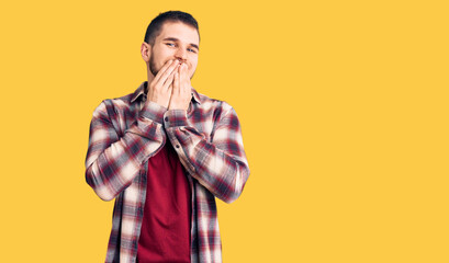Young handsome man wearing casual shirt laughing and embarrassed giggle covering mouth with hands,...