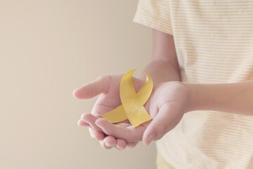 Hands holding yellow gold ribbon, Sarcoma Awareness, Bone cancer, childhood cancer awareness,...