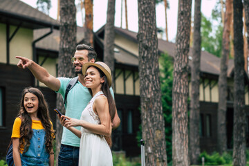 Look this way. A photo of a united glad family on a summer weekend staying outdoor near hotel,...