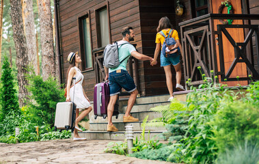 Going up stairs. A photo of a smiling travelling summer dressed family with suitcases and backpacks coming to the hotel, going up stairs.