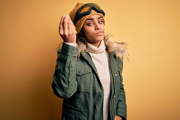 Young african american afro skier girl wearing snow sportswear and ski goggles Doing Italian gesture with hand and fingers confident expression