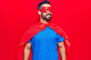 Young hispanic man wearing super hero costume looking to side, relax profile pose with natural face and confident smile.