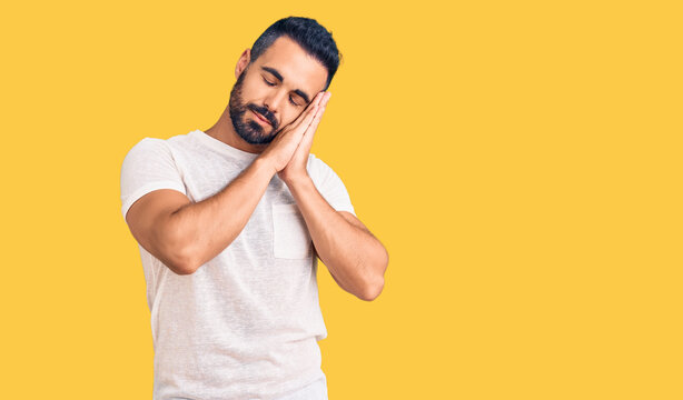 Young hispanic man wearing casual clothes sleeping tired dreaming and posing with hands together while smiling with closed eyes.