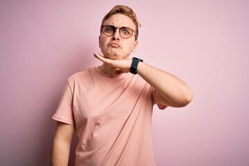 Young handsome redhead man wearing casual t-shirt standing over isolated pink background cutting throat with hand as knife, threaten aggression with furious violence