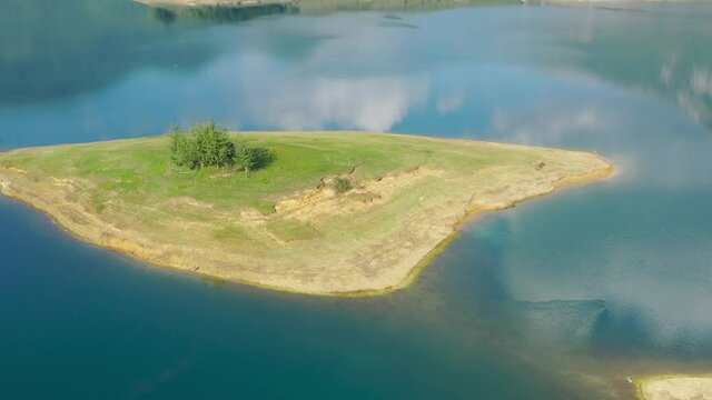 Rama Lake in Bosnia and Herzegovina with heron bird landing on Luke island on a calm day, Aerial Pan left shot