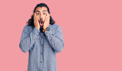 Young arab man wearing casual clothes afraid and shocked, surprise and amazed expression with hands on face
