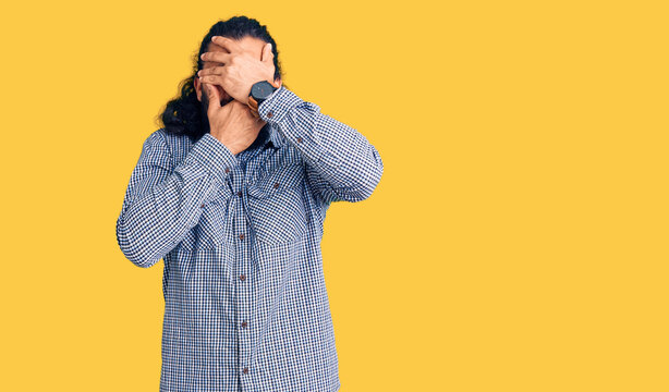 Young arab man wearing casual clothes covering eyes and mouth with hands, surprised and shocked. hiding emotion