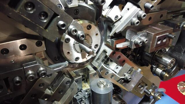 Automatic CNC bending machine. Manufacturing of a torsion spring. Cold industrial color
