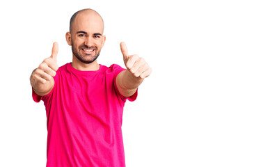 Naklejka premium Young handsome man wearing casual t shirt approving doing positive gesture with hand, thumbs up smiling and happy for success. winner gesture.