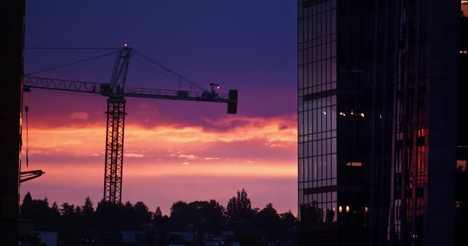 Seattle sunrise silhouettes crane and building in the morning, the crane already at work  