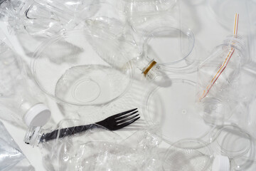 Flatlay composition with used plastic bottles, containers, forks, spoons, egg packaging, caps over white background