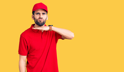 Young handsome man with beard wearing delivery uniform cutting throat with hand as knife, threaten...