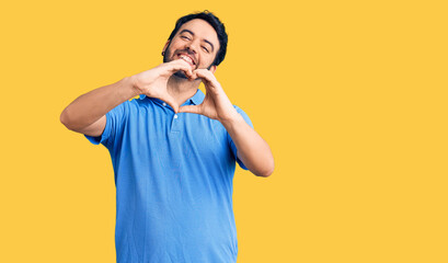 Young hispanic man wearing casual clothes smiling in love doing heart symbol shape with hands. romantic concept.