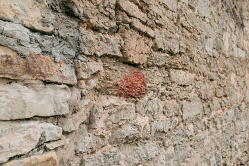 An old medieval stone wall, grass and moss on it. Wallpaper, natural background, copy space, soft focus.