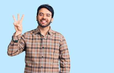 Young hispanic man wearing casual clothes showing and pointing up with fingers number three while smiling confident and happy.