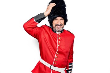 Middle age handsome wales guard man wearing traditional uniform over white background smiling confident touching hair with hand up gesture, posing attractive and fashionable