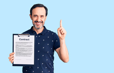 Middle age handsome man holding clipboard with contract document surprised with an idea or question pointing finger with happy face, number one