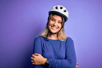 Young beautiful blonde cyclist woman wearing bike security helmet over purple background happy face smiling with crossed arms looking at the camera. Positive person.