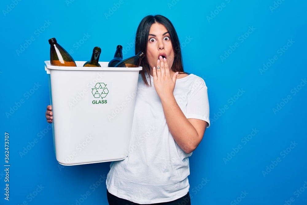 Sticker young beautiful woman recycling glass bottles on wastebasket to care environment covering mouth with