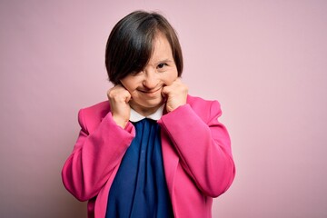 Young down syndrome business woman over pink background covering ears with fingers with annoyed...