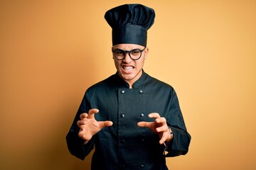 Young brazilian chef man wearing cooker uniform and hat over isolated yellow background smiling...