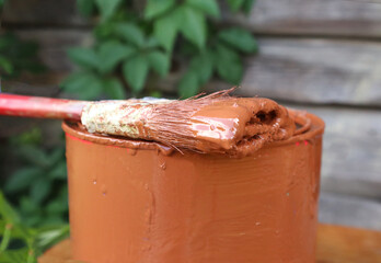 Paint brush on a Bank with paint close-up, side view on a wooden background-the concept of carrying out repair work in the country or on a plot of land