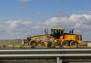 Obraz premium Grader yellow. Grader road construction, industrial machine for the construction of new roads.