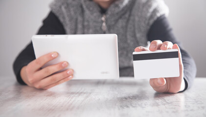 Girl showing credit card and tablet in office. Business