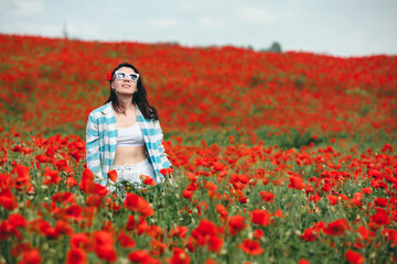 Fototapeta na wymiar young pretty woman in sunglasses at the field of poppy flowers