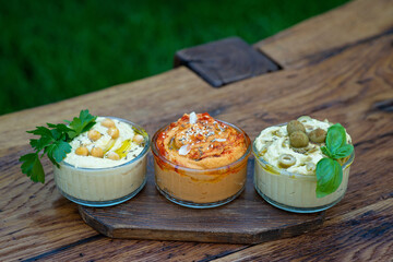 Three types of classic appetizer hummus with paprika and garlic, olives, chickpeas, tahini, olive...