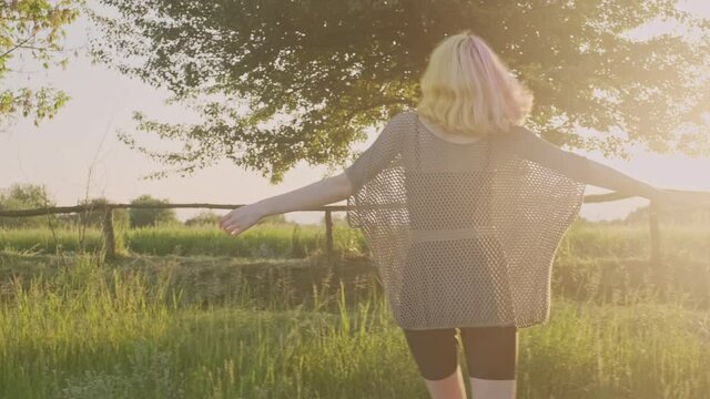 Summer vacation, happy teenage girl walking on country road with ukulele guitar, fashionable hipster with dyed hair enjoys the weekend and nature, countryside background