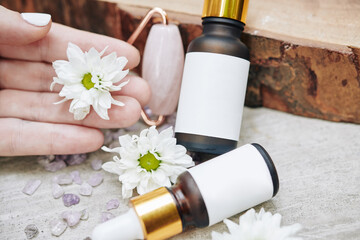Close-up image of rose quartz roller and flower essential oils for face massage