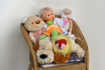 Bergen, Netherlands, January 20, 2020. Plush, stuffed animal toy collection on a wicker chair with a white gray background. Includes a doll, teddy bear, dog, lion and a hare.   