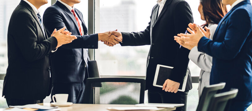 Image two asian business partners in elegant suit successful handshake together in front of group of casual business clapping hands in modern office.Partnership approval and thanks gesture concept