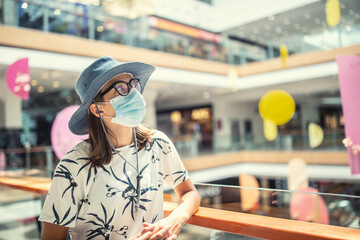 Fototapeta premium Young woman is protected from coronavirus with a protective mask in the interior of the supermarket