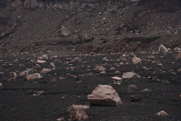 view of part of active volcano crater where expelled rocks and sandy surface are observed