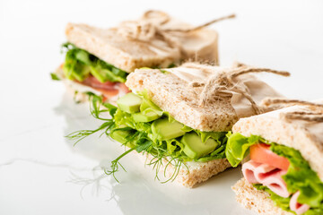 selective focus of fresh green sandwiches with avocado and meat on white surface