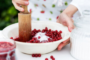 Woman prepares jam of the raw  red currants, female makes marmalade for dishes, healthy eating and  cooking concept