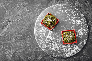 Bowls with tasty seaweed on dark background