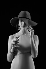 Beautiful young woman with martini on dark background