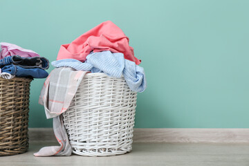 Baskets with dirty clothes near color wall