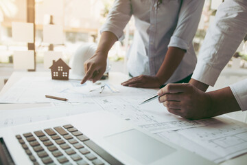 Two architect working at construction site and compass drawing pointing on blueprint with...