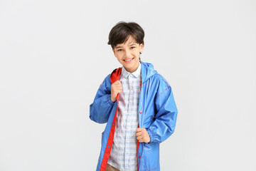 Cute little boy in raincoat on light background