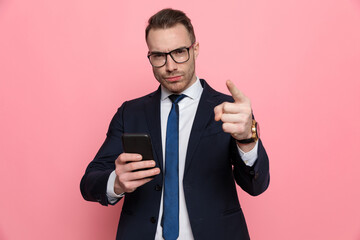 young elegant man in suit reading emails and pointing finger