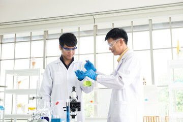 Science, Chemistry, Technology, Biology and Laboratory concept - Portrait of Asian senior and junior scientist is testing an experiment result in petri dish in their laboratory.