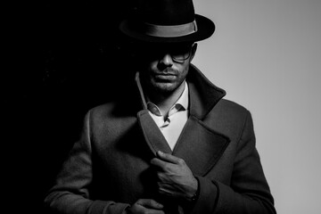 dramatic cool guy wearing hat and glasses and fixing coat