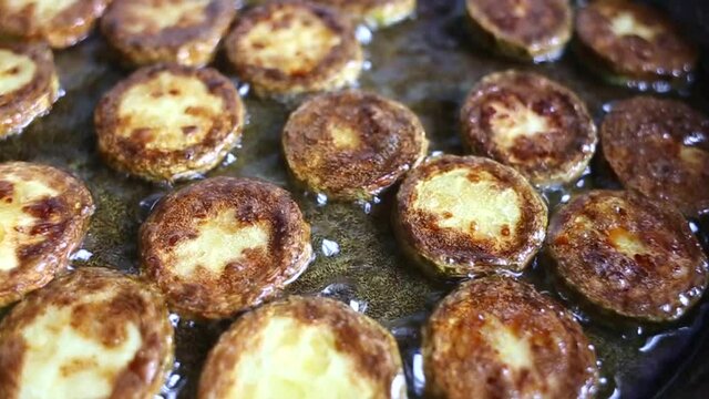 The process of frying zucchini, sliced in circles in boiling oil in a pan close-up