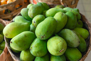 green mangoes lying in a basket on the market.