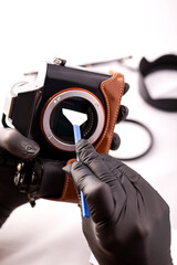 A gloved photographer takes care of photographic equipment with special tools. The concept of a profession photographer.
